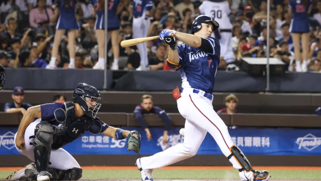 棒球選手身穿白橘球衣在比賽中滑壘進壘畫面